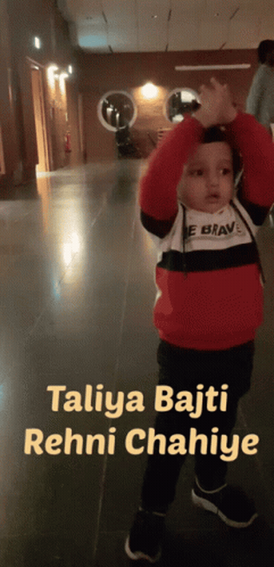 A Little Boy Standing In A Hallway With The Words " Taliya Bajti Rehni Chahiye " Above Him GIF