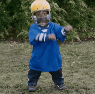 A Little Boy Wearing A Blue Shirt And A Yellow Helmet Is Dancing GIF