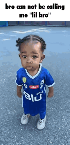 A Little Boy Wearing A Blue Soccer Jersey Is Standing On The Ground . GIF