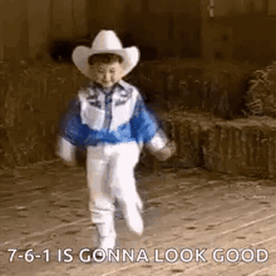 A Little Boy Wearing A Cowboy Hat And A Blue Jacket Is Walking On A Sidewalk . GIF