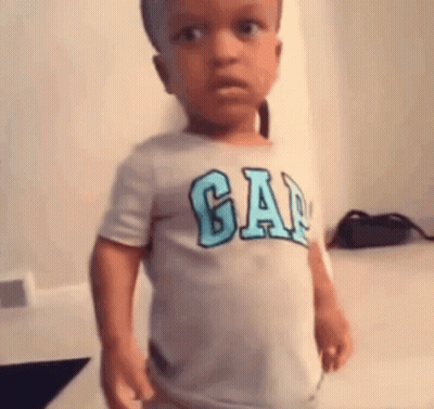 A Little Boy Wearing A Gap T-Shirt Is Standing In A Room . GIF