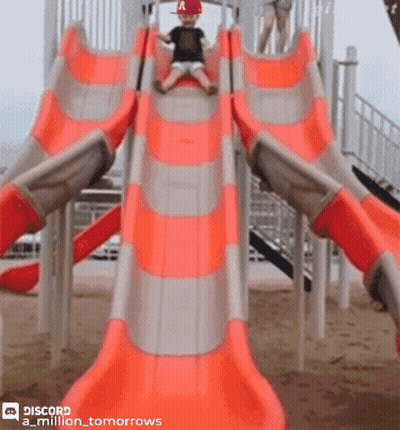 A Little Boy Wearing A Red Hat Is Sliding Down An Orange Slide GIF