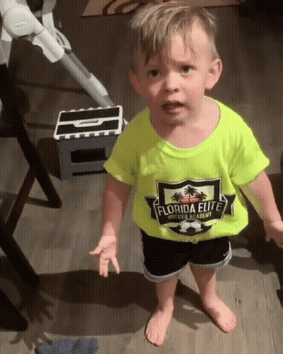 A Little Boy Wearing A Yellow Shirt That Says Florida Elite Is Standing On A Wooden Floor . GIF