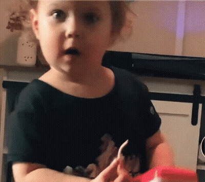 A Little Girl In A Black Shirt Is Holding A Piece Of Paper GIF