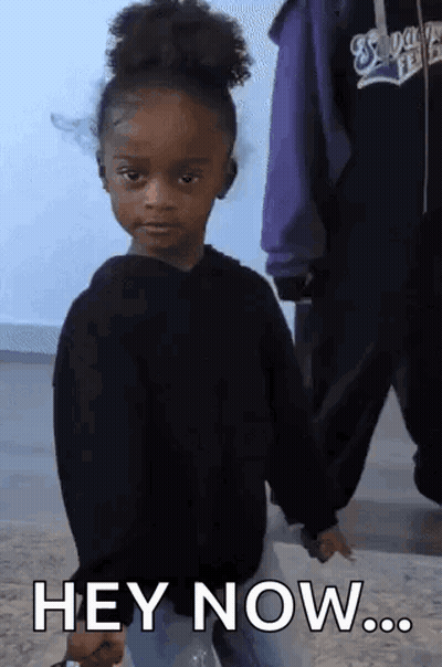 A Little Girl In A Black Sweater Is Holding A Bottle And Says Hey Now GIF