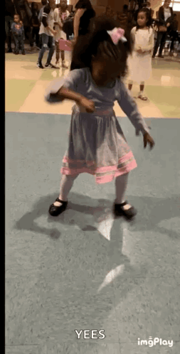 A Little Girl In A Blue And Pink Dress Is Dancing In A Hallway With The Words Yees Visible In The Corner GIF