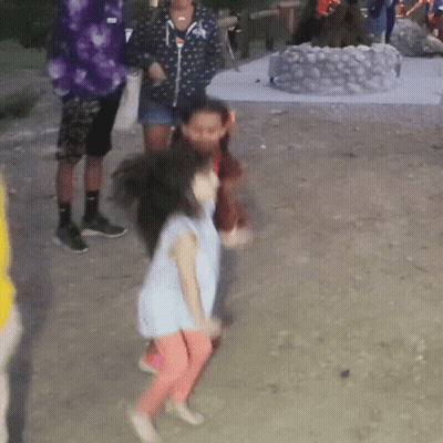 A Little Girl In A Blue Shirt And Pink Pants Is Dancing In The Dirt GIF