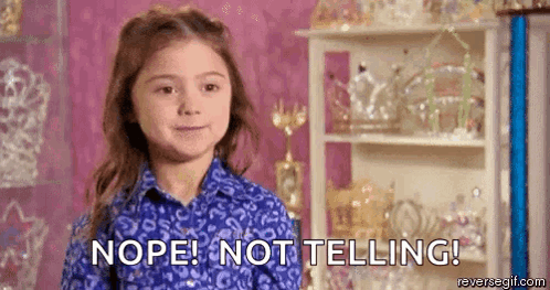 A Little Girl In A Blue Shirt Is Standing In Front Of A Shelf And Saying Nope ! Not Telling ! GIF