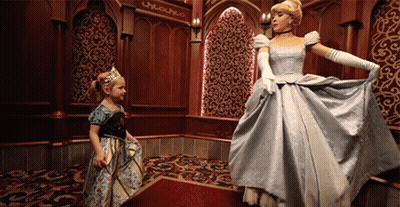 A Little Girl In A Dress Is Standing Next To A Cinderella GIF