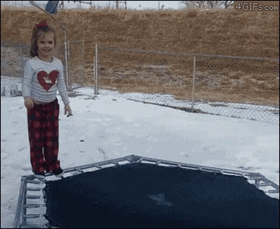 A Little Girl In A Heart Shirt Is Jumping On A Trampoline In The Snow GIF