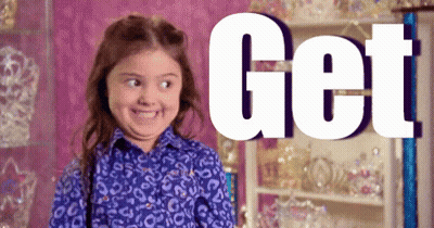 A Little Girl In A Leopard Print Shirt Is Smiling In Front Of A Sign That Says Get . GIF
