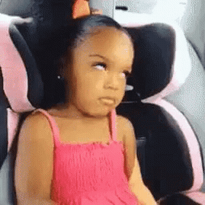 A Little Girl In A Pink Dress Is Sitting In A Car Seat And Making A Funny Face . GIF