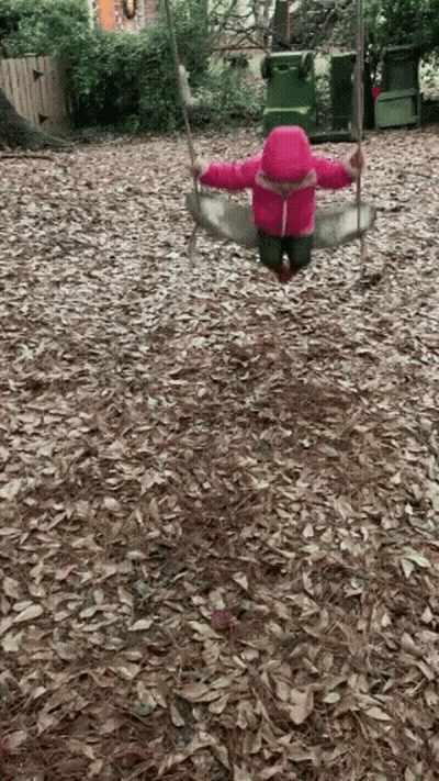 A Little Girl In A Pink Jacket Swings On A Swing GIF