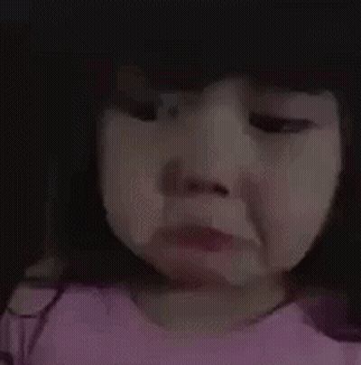 A Little Girl In A Pink Shirt Is Crying And Making A Sad Face . GIF