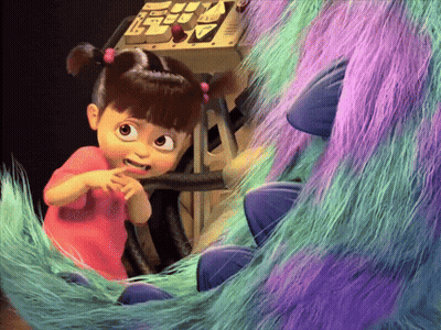 A Little Girl In A Pink Shirt Is Sitting Next To A Purple And Green Monster GIF