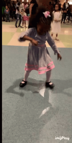A Little Girl In A Purple And Pink Dress Is Dancing In A Room With Other Children GIF