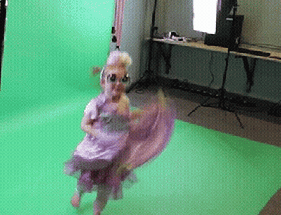 A Little Girl In A Purple Dress Is Dancing In Front Of A Green Background GIF