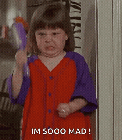 A Little Girl In A Red And Purple Dress Is Making A Funny Face While Holding A Purple Object . GIF