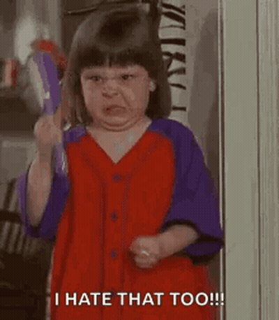 A Little Girl In A Red And Purple Shirt Is Holding A Toothbrush And Making A Funny Face . GIF
