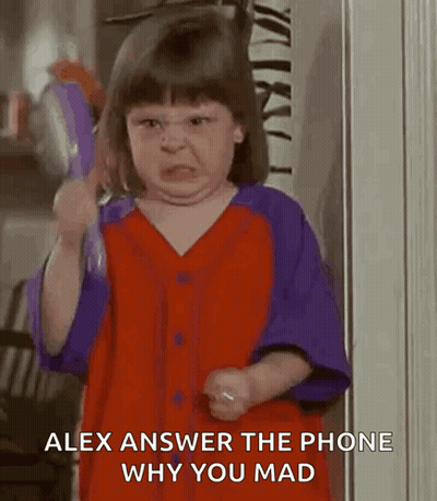 A Little Girl In A Red And Purple Shirt Is Making A Funny Face While Holding A Toy . GIF
