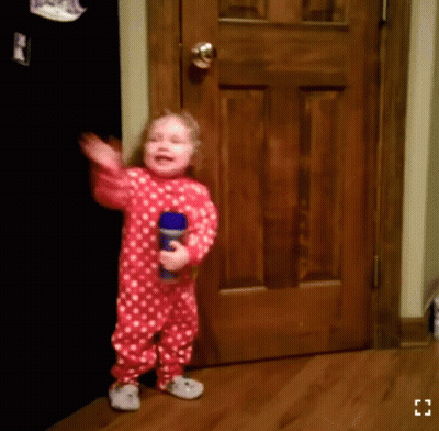 A Little Girl In A Red And White Polka Dot Pajamas Is Holding A Blue Bottle GIF