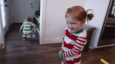 A Little Girl In A Red And White Striped Pajama Stands Next To A Toddler In A Green And White Striped Pajama GIF
