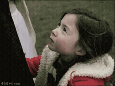A Little Girl In A Red Jacket Is Looking Up At The Sky GIF