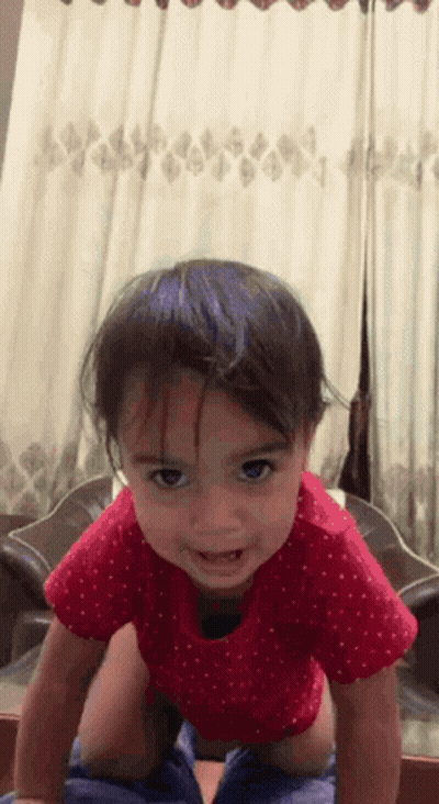 A Little Girl In A Red Polka Dot Shirt Is Crawling On The Floor GIF