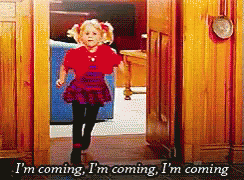 A Little Girl In A Red Shirt Is Running Through A Doorway And Says I 'M Coming I 'M Coming GIF