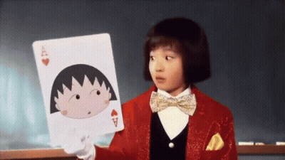A Little Girl In A Red Suit And Bow Tie Is Holding A Playing Card With A Cartoon Character On It . GIF