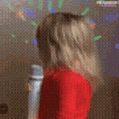 A Little Girl In A Red Sweater Is Holding A Microphone . GIF
