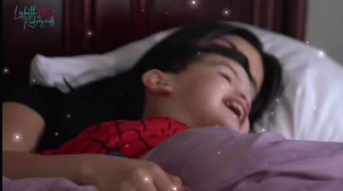 A Little Girl In A Spiderman Costume Is Laying In Bed With Her Mother GIF