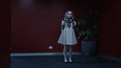 A Little Girl In A White Dress Is Dancing In Front Of A Potted Plant GIF