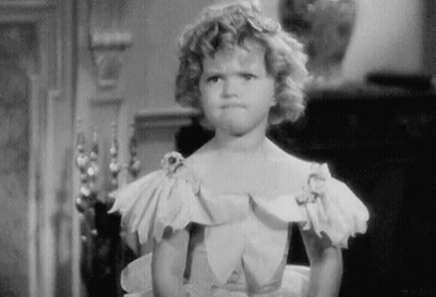 A Little Girl In A White Dress Is Making A Funny Face GIF