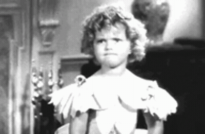 A Little Girl In A White Dress Is Standing In Front Of A Mirror In A Black And White Photo . GIF
