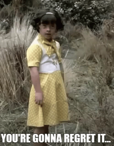 A Little Girl In A Yellow Dress Is Standing In The Grass With The Words You 'Re Gonna Regret It .. GIF