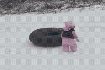 A Little Girl In Pink Standing Next To A Black Tire GIF