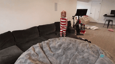 A Little Girl In Striped Pajamas Stands On A Couch GIF