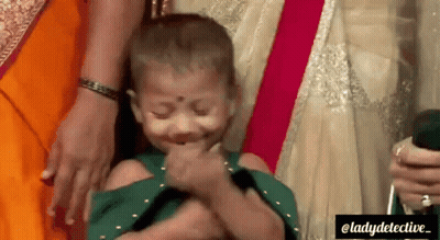 A Little Girl Is Being Held By A Woman And Making A Funny Face . GIF