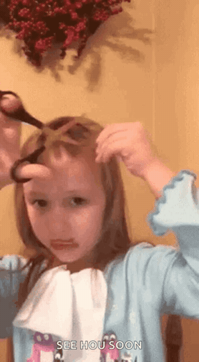 A Little Girl Is Cutting Her Hair With Scissors And Making A Face . GIF