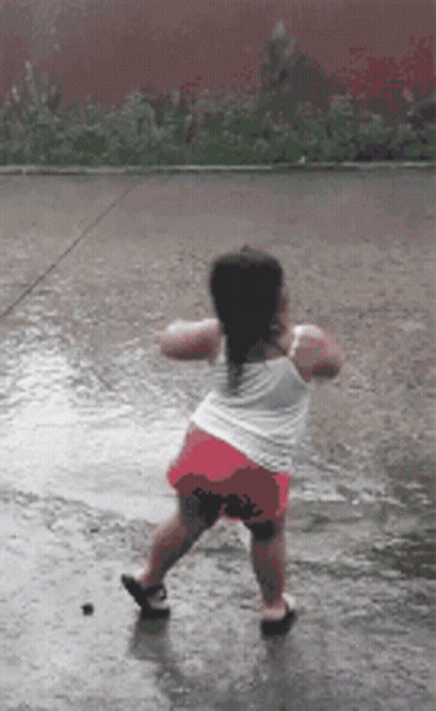 A Little Girl Is Dancing In A Puddle Of Water GIF
