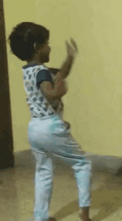 A Little Girl Is Dancing In A Room With A Yellow Wall Behind Her . GIF