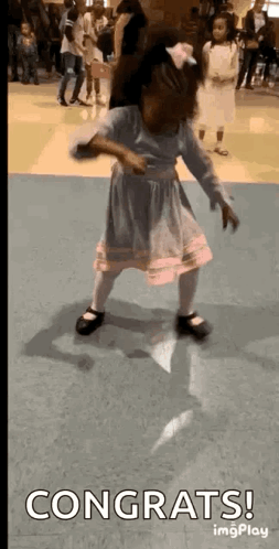 A Little Girl Is Dancing In A Room With The Words `` Congrats '' Written On The Bottom . GIF