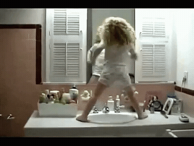 A Little Girl Is Dancing In Front Of A Bathroom Sink GIF