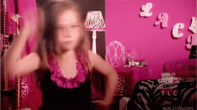 A Little Girl Is Dancing In Front Of A Pink Wall With The Word Tlc On It GIF