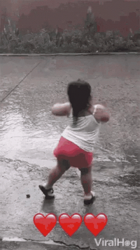 A Little Girl Is Dancing In The Rain With Red Hearts . GIF