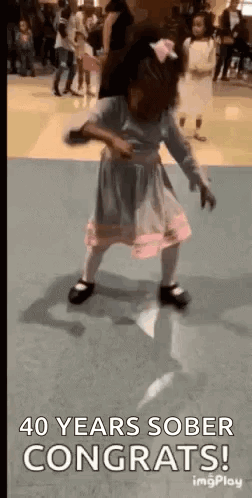 A Little Girl Is Dancing On A Dance Floor With The Words `` 40 Years Sober Congrats '' . GIF