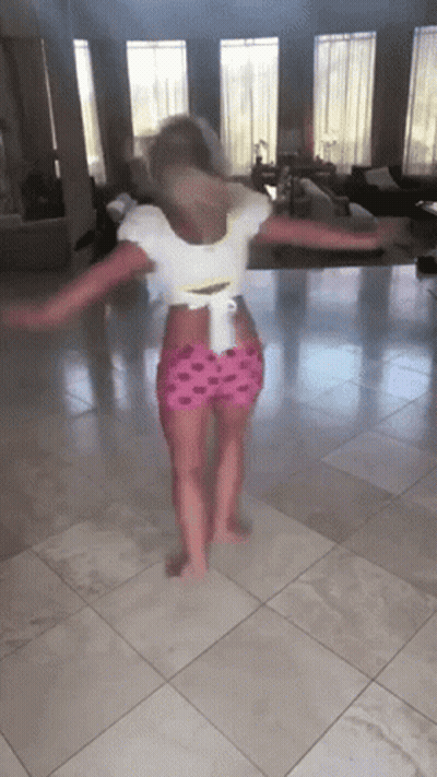 A Little Girl Is Dancing On A Tiled Floor GIF