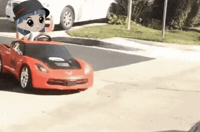 A Little Girl Is Driving A Red Toy Car On The Street GIF