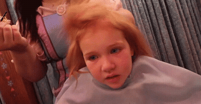 A Little Girl Is Getting Her Hair Cut By A Woman In A Pink Dress GIF